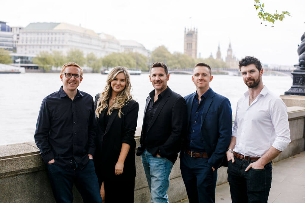 headshot of five team members outside near the water