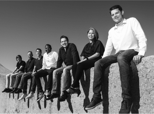 team of professionals wearing business clothes sat on a wall