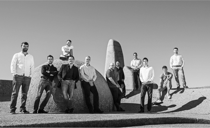 team of business professionals in black and white standing around boulders